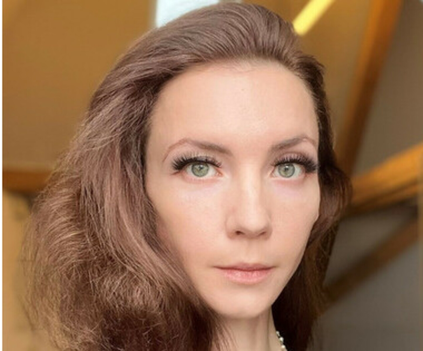 Iuliia Shkrabaliuk hat braune, gewellte lange Haare. Sie trägt ein schwarzes Jacket.