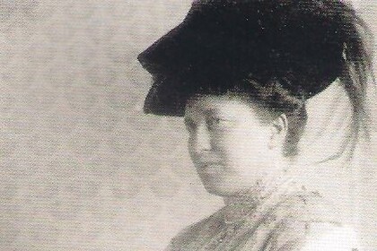 Schwarz-weiß-Abbildung von Julie Bassermann. Sie ist von der Seite zu sehen, trägt einen dunklen Hut und ein langes Kleid.