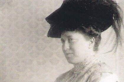 Schwarz-weiß-Abbildung von Julie Bassermann. Sie ist von der Seite zu sehen, trägt einen dunklen Hut und ein langes Kleid.