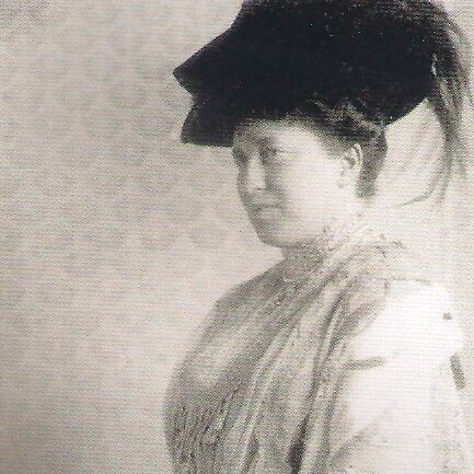 Schwarz-weiß-Abbildung von Julie Bassermann. Sie ist von der Seite zu sehen, trägt einen dunklen Hut und ein langes Kleid.