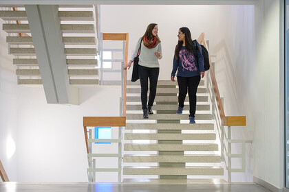 Zwei Studentinnen unterhalten sich und laufen die Treppe im Gebäude L 1 runter.
