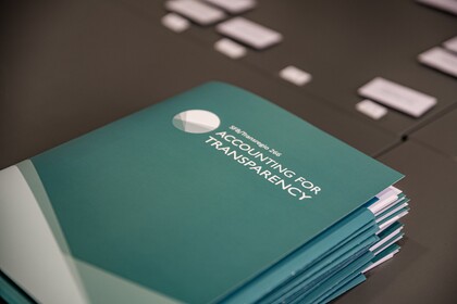 Türkisfarbene Mappen liegen auf einem schwarzen Tisch. Die Mappe haben die weiße Aufschrift "SFB/Transregio 266, Accounting for Transparency".