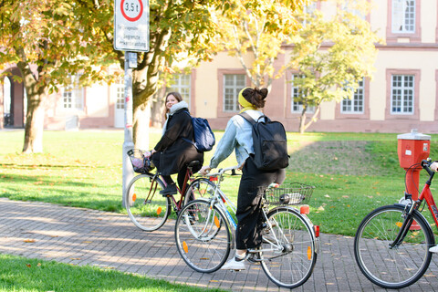 Three female students on their bicycles in the autumn afternoon sun.