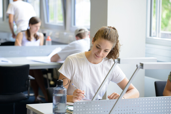 Eine Studentin sitzt an einem Tisch und lernt.