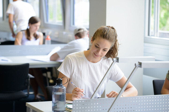 Eine Studentin sitzt an einem Tisch und lernt. Link: BaPsy-DGPs Anmeldung