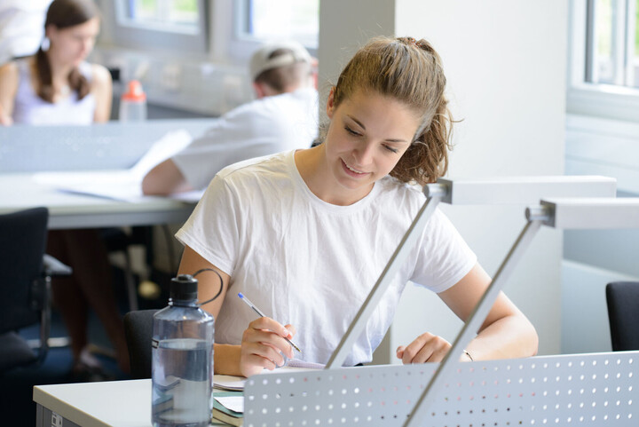 Eine Studentin sitzt in der Bibliothek und lernt.
