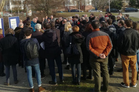 Rektor Prof. Dr. Thomas Puhl präsentiert die Pläne zur Bebauung des Friedrichparks. Um ihn herum sind Zuschauende.  