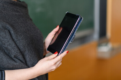Frau vor Tafel mit Tablet in den Händen