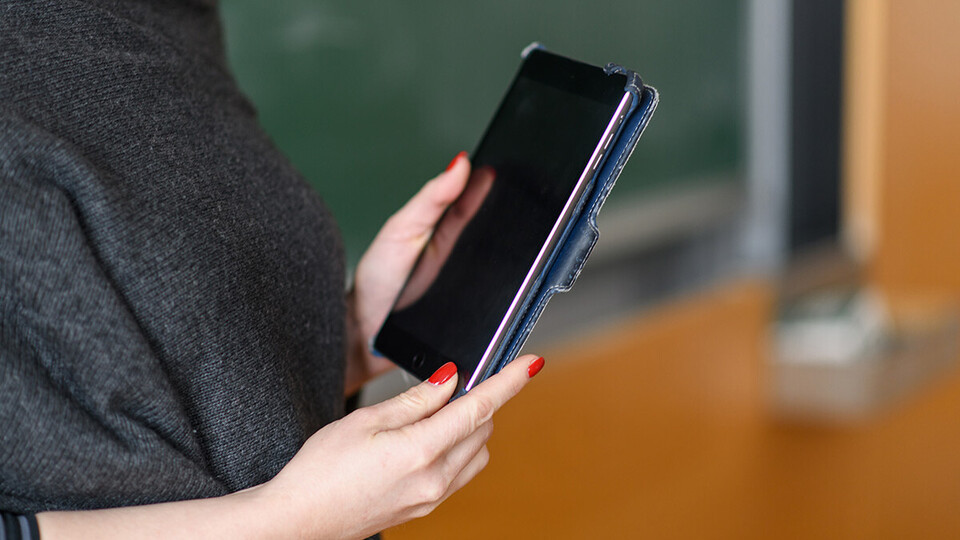 Frau vor Tafel mit Tablet in den Händen