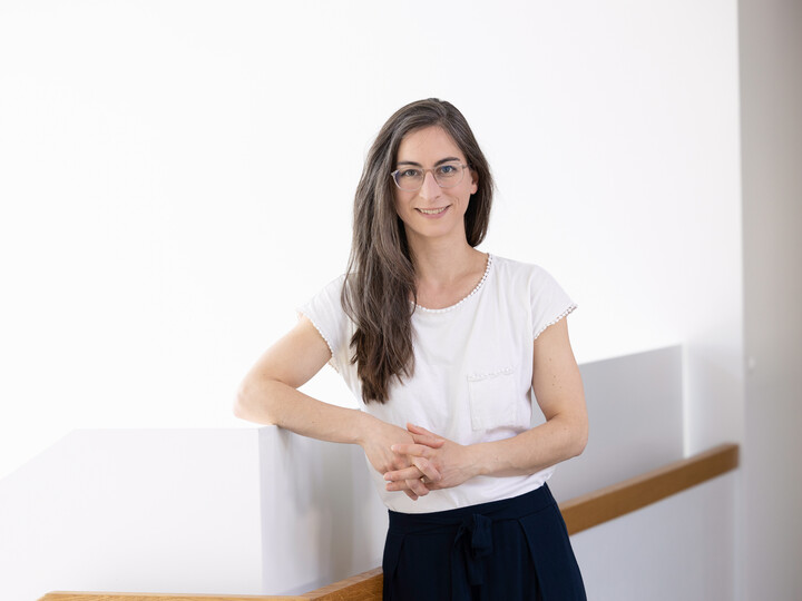 Teresa Naab steht neben einer Treppe und hat einen Arm auf der Treppe abgestützt.