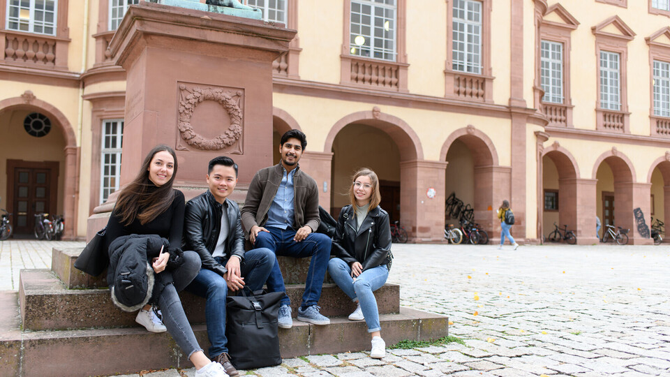 Eine Gruppe Studierender sitzt im Ehrenhof des Schlosses