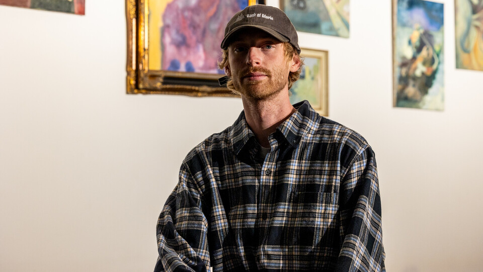 Jake Sandquist steht vor Bildern seiner Ausstellung