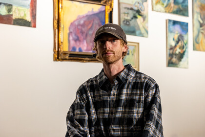 Jake Sandquist steht vor Bildern seiner Ausstellung