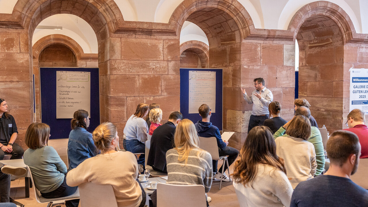 Veranstaltung in den Katakomben des Schlosses: Eine Person spricht im Stehen zu einer Gruppe, die in einem lockeren Stuhlkreis sitzt und aufmerksam zuhört.