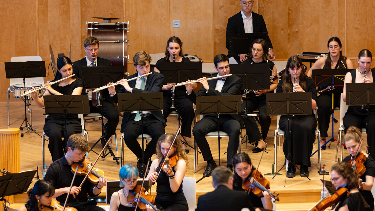 Auftritt des Uniorchesters. Studierende sind schwarz gekleidet und spielen jeweils ein Instrument