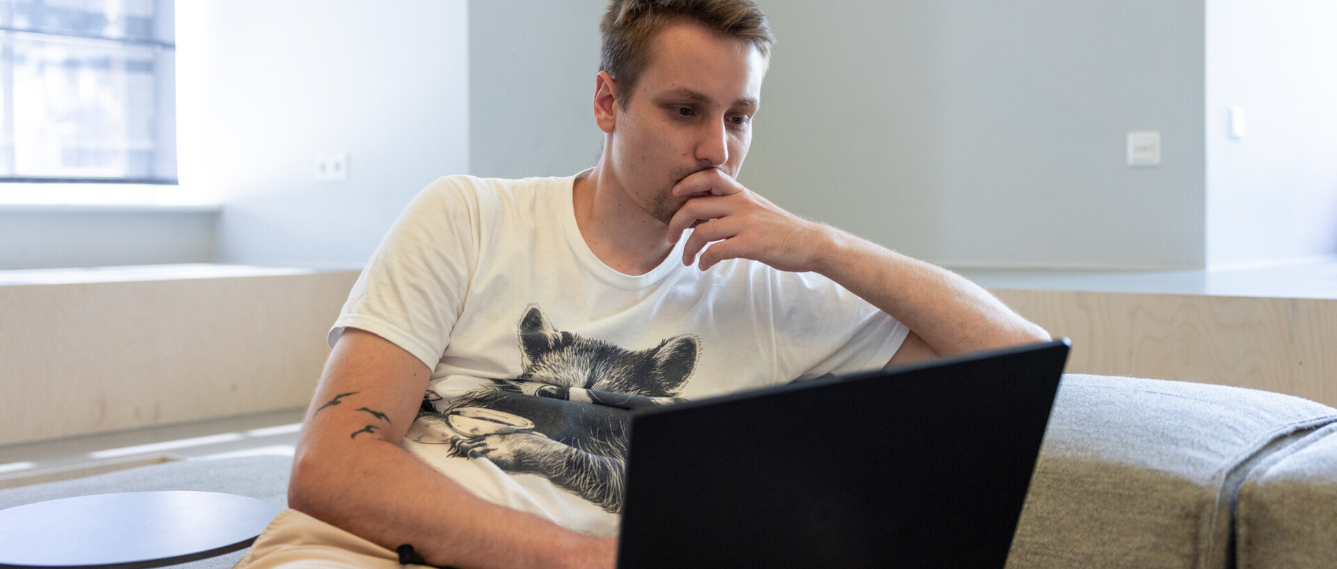 Studierender arbeitet am Laptop auf einem Sofa 