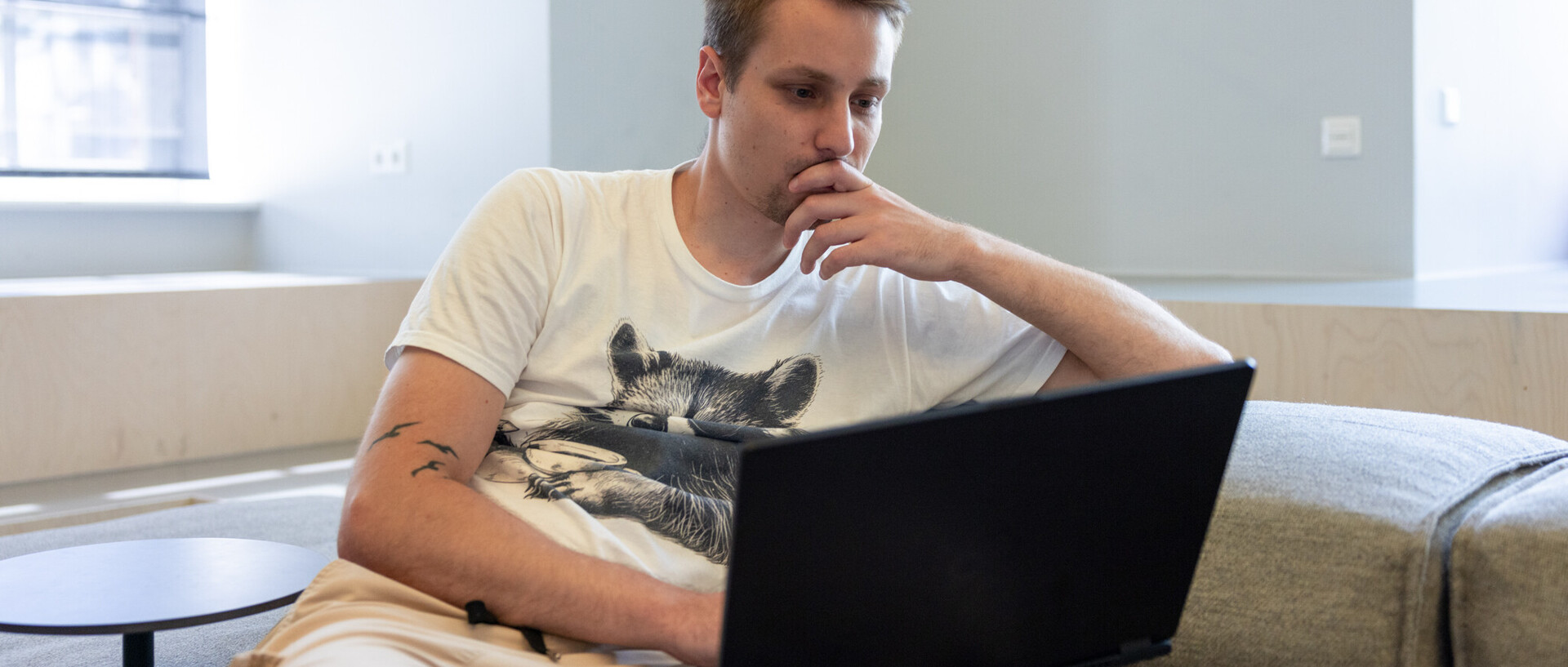 Studierender arbeitet am Laptop auf einem Sofa 
