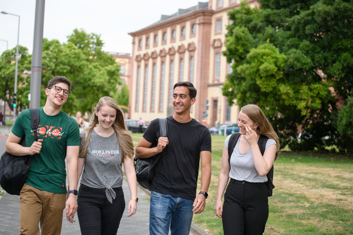 Eine Gruppe lachender Studierender. Im Hintergrund das Mannheimer Schloss.