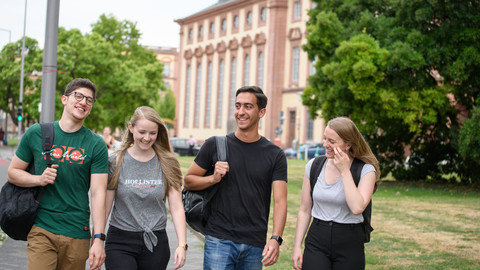 Eine Gruppe lachender Studierender. Im Hintergrund das Mannheimer Schloss.