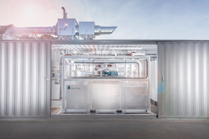 An industrial electrolysis plant labelled ‘Sunfire’ stands between two container walls.