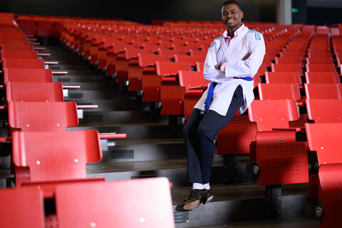 Ein Studierender in einem Vorlesungssaal trägt eine Karatejacke über seiner formellen Kleidung.