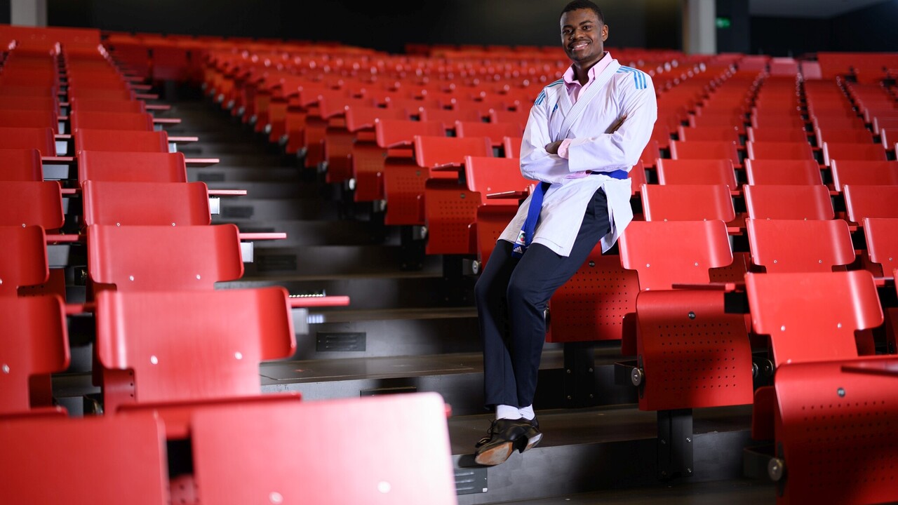 Ein Studierender in einem Vorlesungssaal trägt eine Karatejacke über seiner formellen Kleidung.