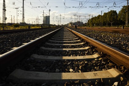 Blick auf eine Zugschiene im Abendlicht. Im Hintergrund sind ein paar Hochhausgebäude des Mannheimer Bahnhof erkennbar.