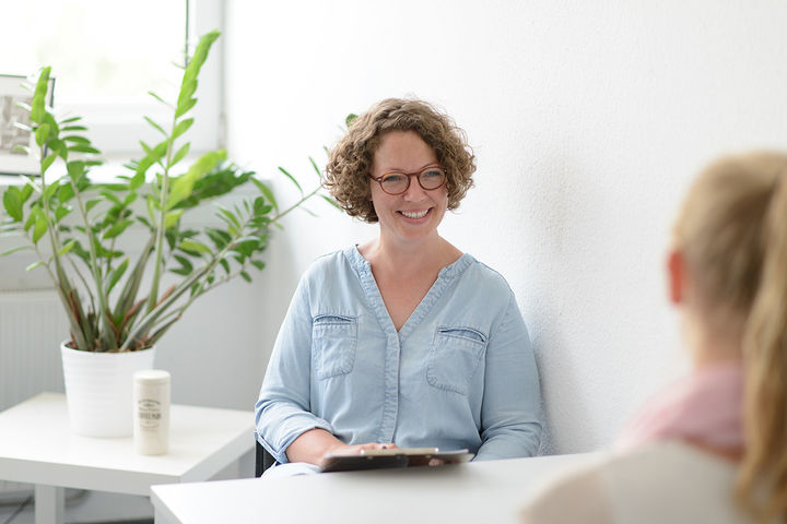 two people sitting in a clean, tidy room talking to each other