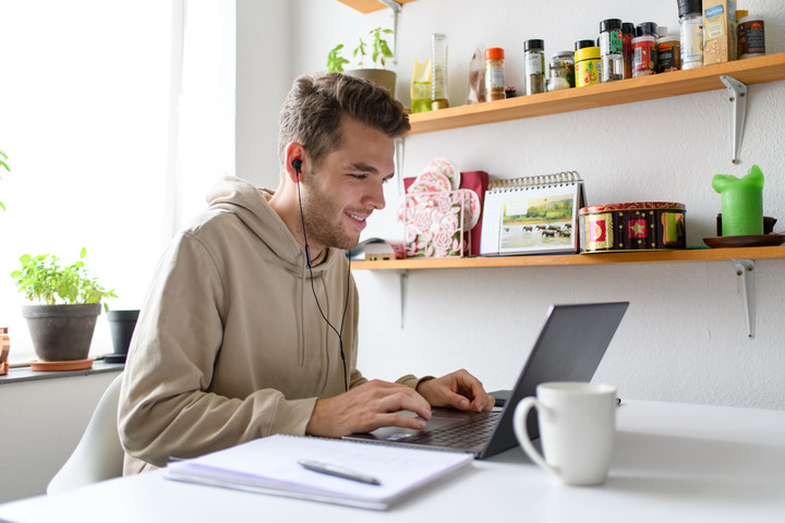 Student sitting in his kitchen in front of a laptop