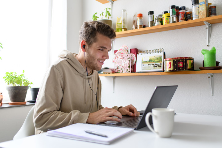 Student sitting in his kitchen in front of a laptop