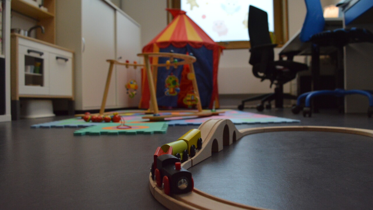Eltern-Kinder-Zimmer der Universität Mannheim. Im Hintegrund Schreibtisch für Elternteil und Kind. Auf dem Boden liegen Spielsachen.