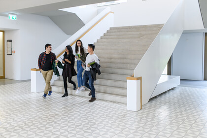 International Studierende B6_Anna Logue Vier Studierende laufen eine Treppe des B6-Bauteils der Uni Mannheim runter.