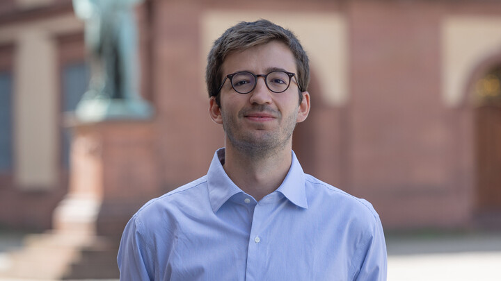 Pablo Arnaiz. He is wearing a blue shirt and is standing on the Ehrenhof in front of the castle.
