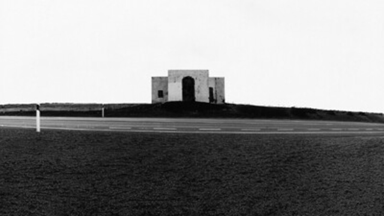 Schwarz-weiß-Foto eines Hauses an einer leeren Schnellstraße.