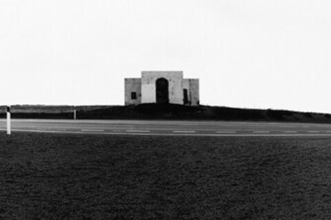 Schwarz-weiß-Foto eines Hauses an einer leeren Schnellstraße.