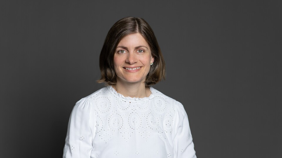 Katrhrine von Graevenitz trägt ein weißes Oberteil und lächelt.