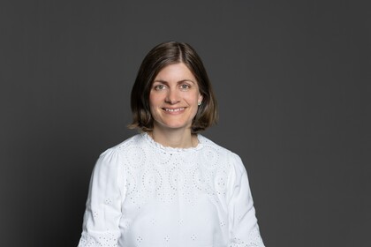 Katrhrine von Graevenitz trägt ein weißes Oberteil und lächelt.