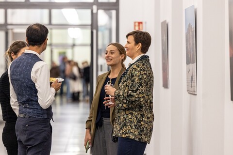 Vier Personen stehen vor den Bildern der Spitzensport-Vernissage. 