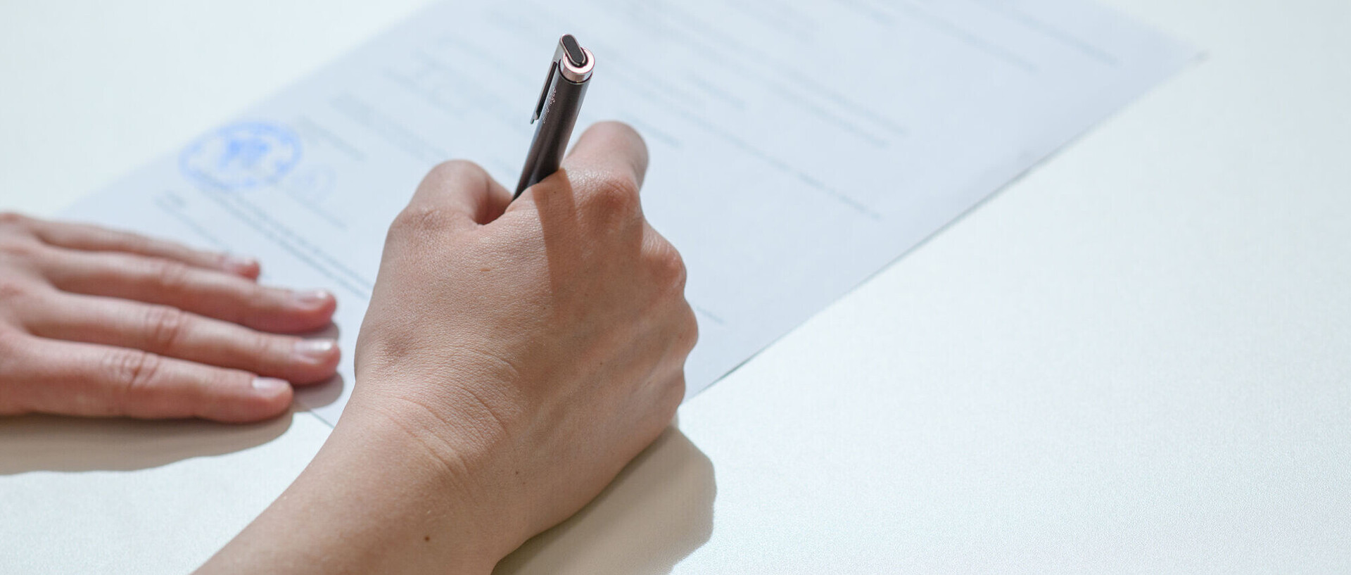 Ein Dokument wird per Hand unterschrieben.