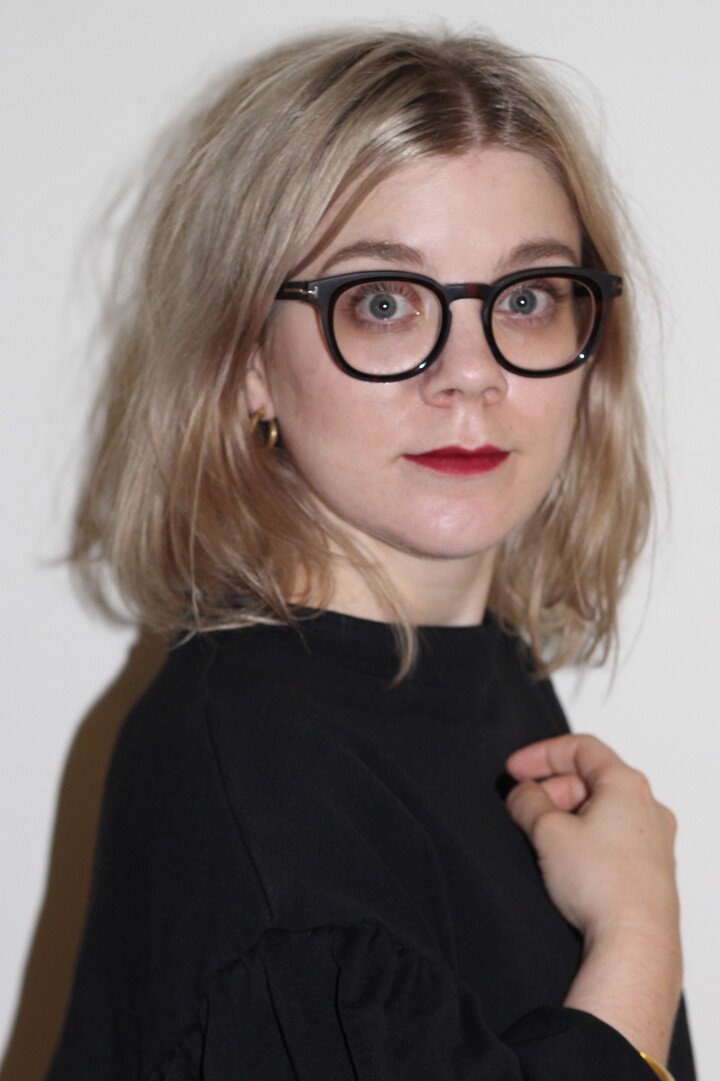 Alex Stolz hat schulterlange blonde Haare und trägt eine große runde schwarze Brille