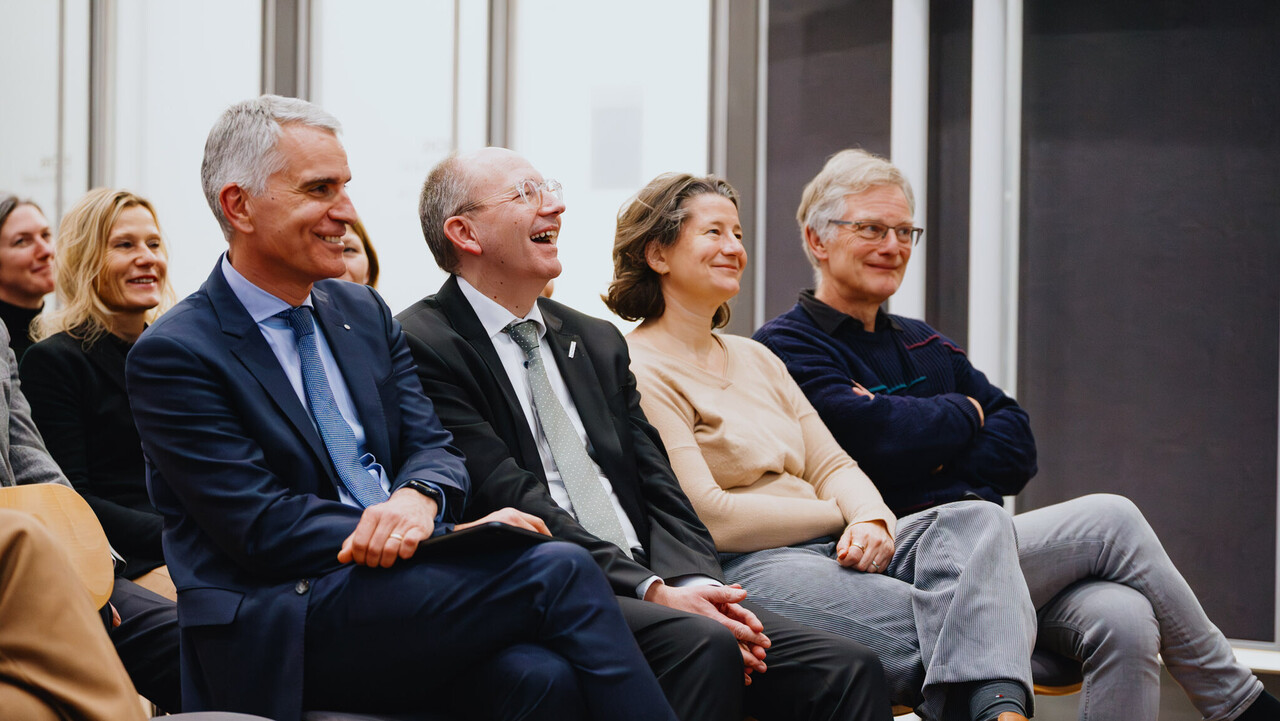 Das Foto zeigt vier Personen in der ersten Reihe der Zuhörenden. Sie lachen. Es sind der Rektor der Universität Mannheim, der Oberbürgermeister der Stadt Mannheim, die Kanzlerin der Universität Mannheim, ein ehemaliger Rektor der Universität Mannheim