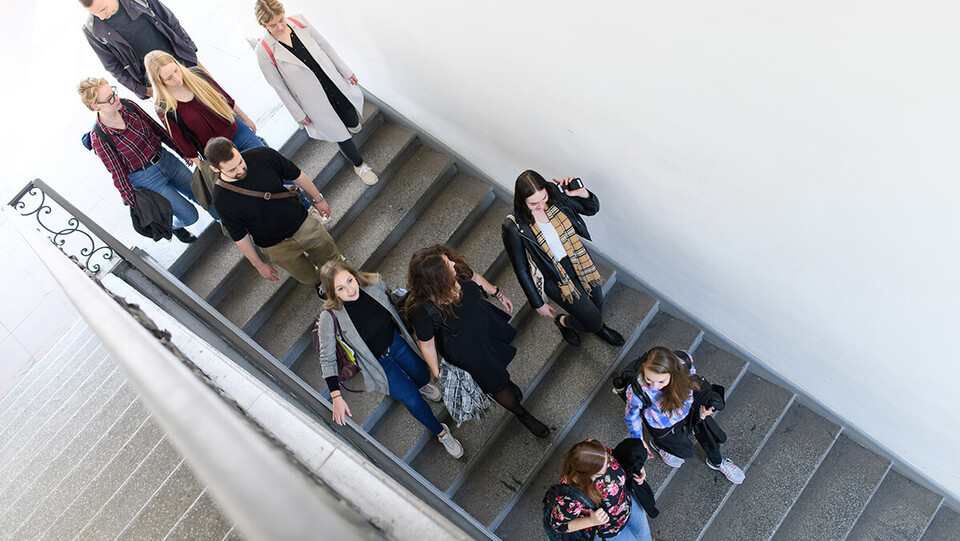 Gruppe Studierender geht eine Treppe im Schloss herunter 