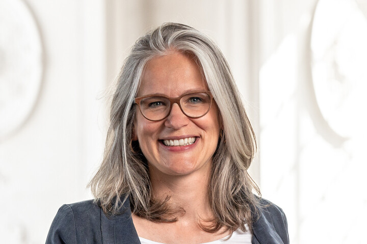 Frau Prof. Jutta Mata hat graue halblange Haare, sie trägt eine braune Brille und einen grauen Blazer.