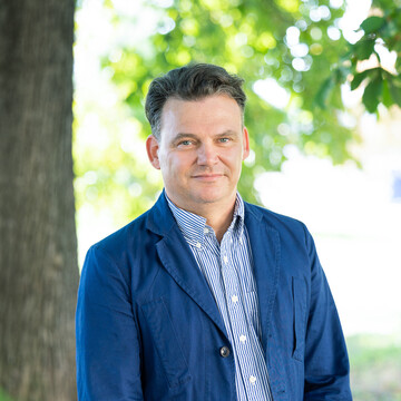  Prof. Henning Hillmann. Er schaut freundlich drein und trägt ein blaues Jacket über einem gestreiften Hemd.