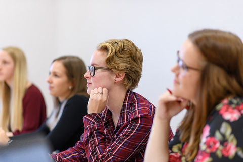 Studentinnen hören bei einem Vortrag zu.