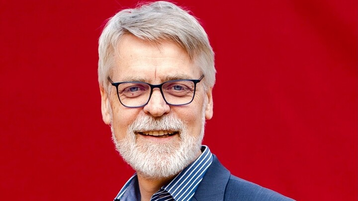 Professor Hartmut Wessler trägt eine Brille, einen blauen Anzug und lächelt in die Kamera.