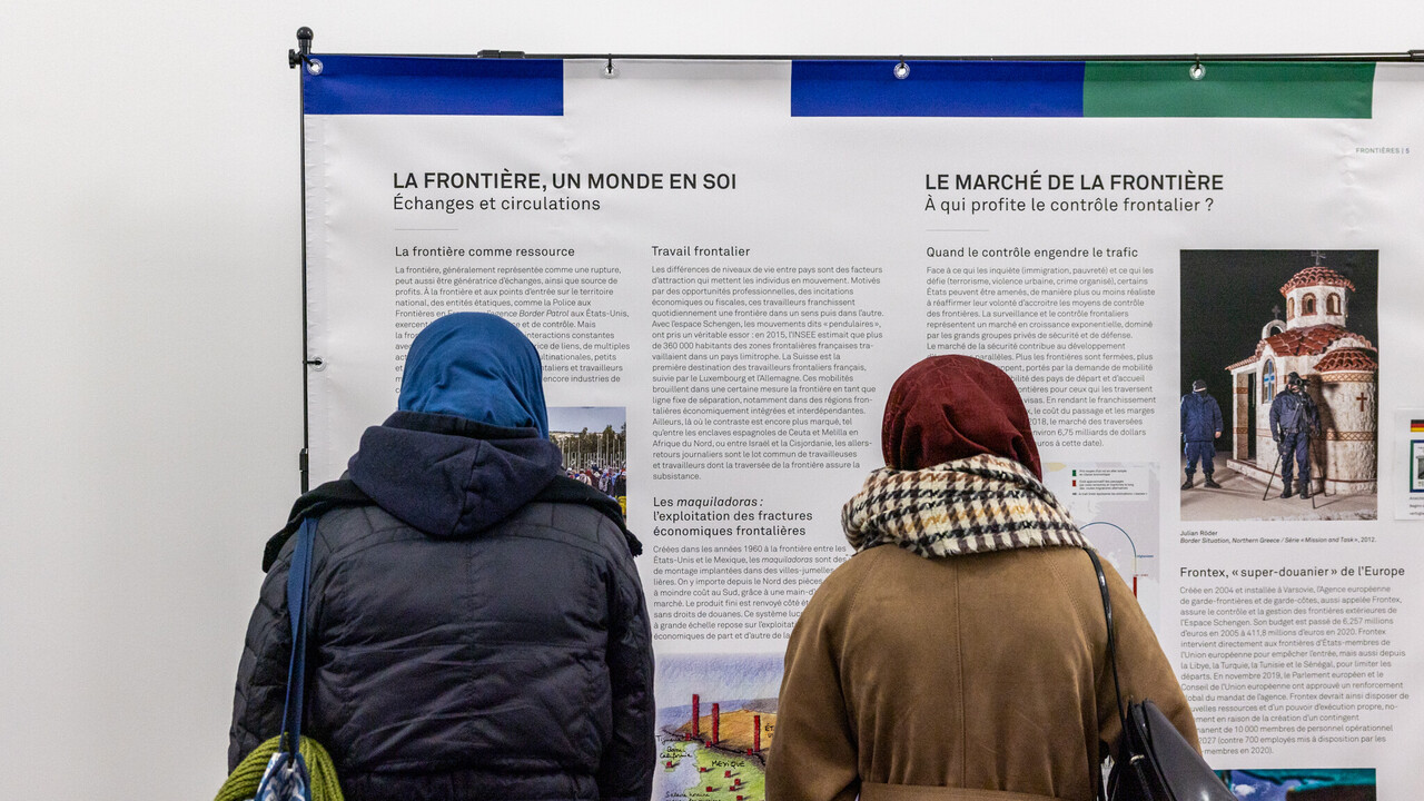 Zwei Personen lesen eine Ausstellungstafel bei einer Vernissage.