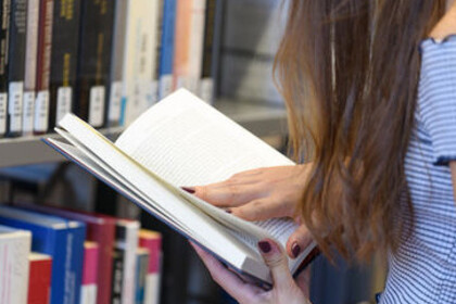 eine weiblich gelesene Studentin hält ein Buch in der Hand