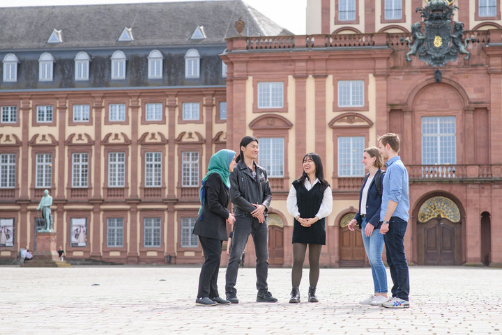 Fünf Persone stehen auf dem Ehrenhof des Schlosses und reden miteinander.