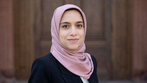 Rezvan Derayati. She is wearing a dark blue jacket and is standing in front of one of the castle doors.